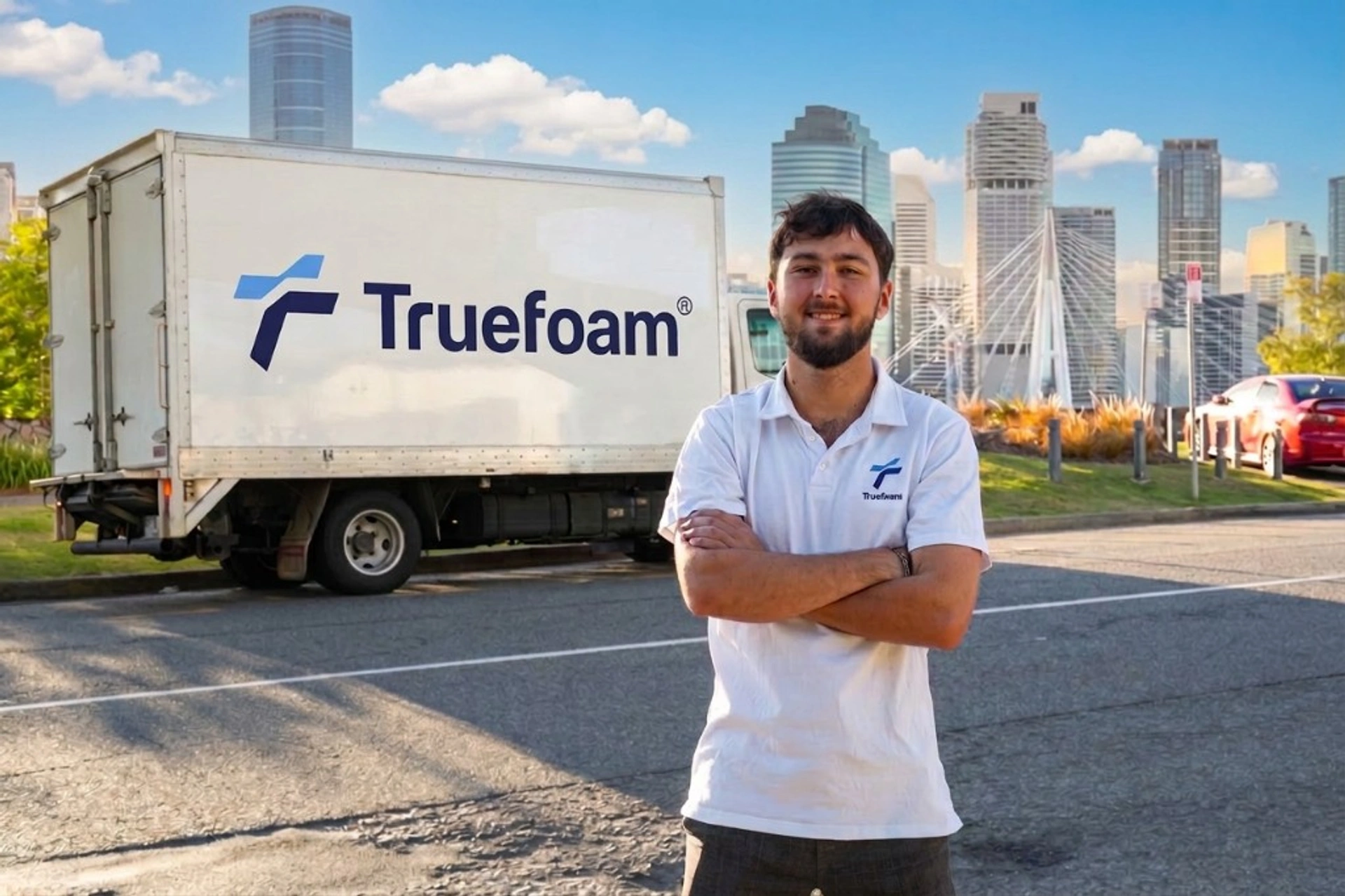 Truefoam team member in front of a branded service truck with Brisbane skyline behind